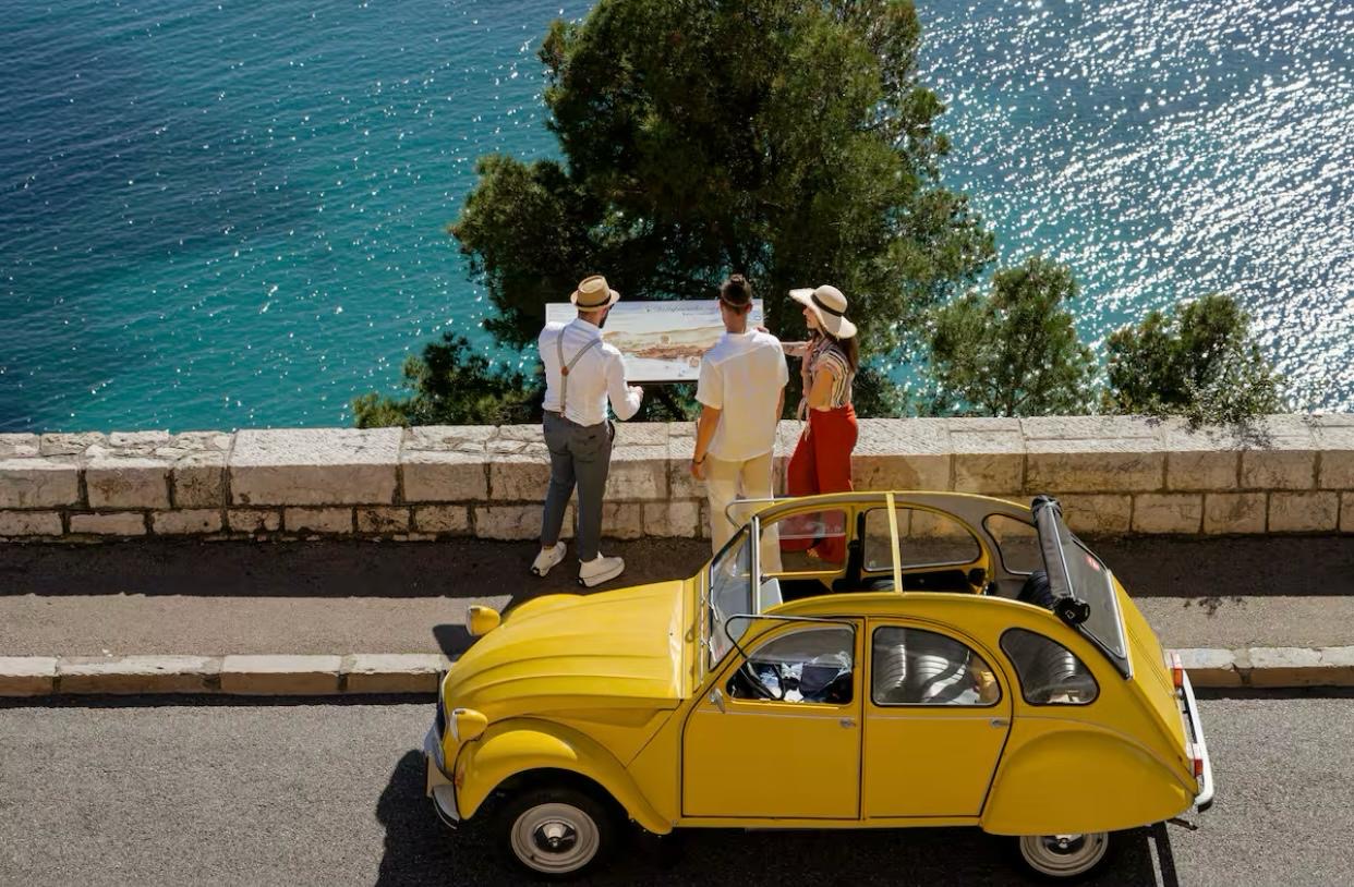 yellow 2CV vintage citroen car over mediterranean sea with driver and clients